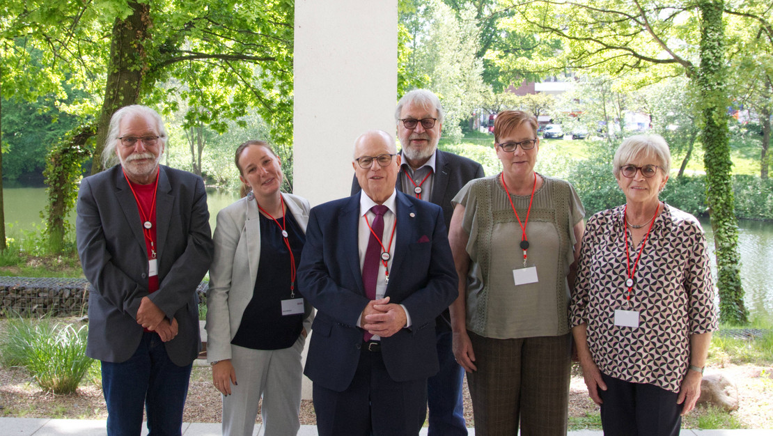 Sechs gewählte Vorstandsmitglieder stehen vor Bäumen des Rote-Kreuz-Krankenhauses.
