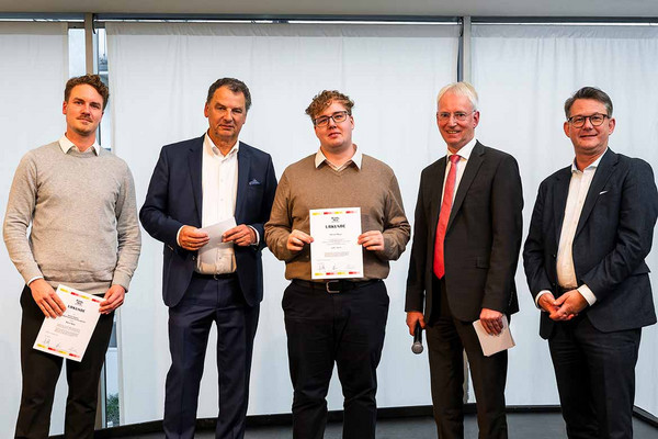 Gruppenbild mit fünf Personen. In der Mitte ein junger Mann mit einer Urkunde in der Hand. 