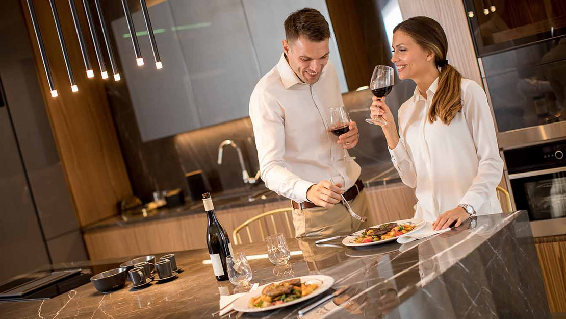 Paar in luxuriöser Wohnung trinkt Wein und isst Steak. 