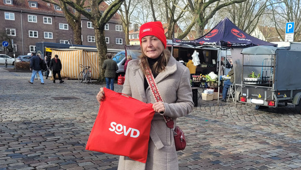 Sara Dahnken präsentiert Infotasche auf Parkplatz des Findorff-Marktes