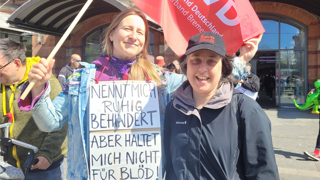 Zwei weibliche SoVD-Mitglieder mit SoVD-Fahne vor dem Hauptbahnhof