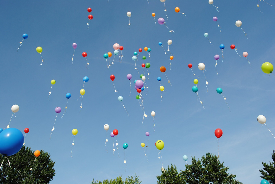 Ballons mit Kärtchen steigen in den Himmel auf