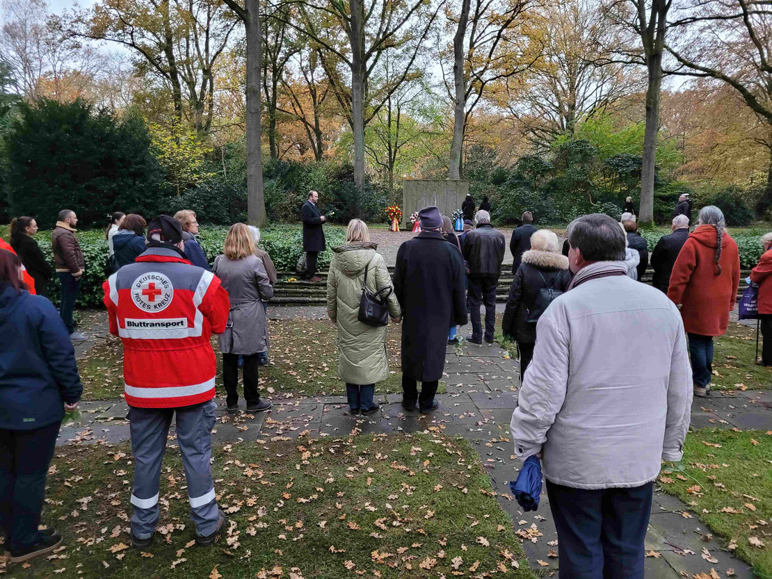 Eine Menschengruppe steht vor dem Gedenkstein auf dem Osterholzer Friedhof