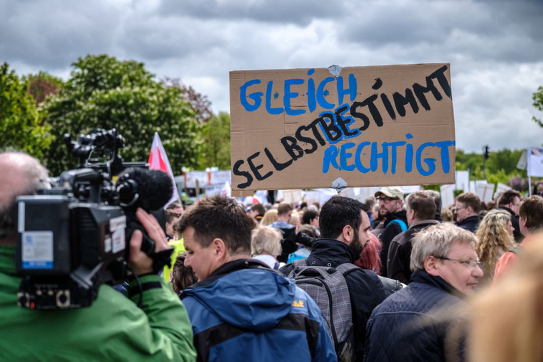 Menschengruppe auf einer Demonstration mit einem Plakat auf dem "Selbstbestimmt" steht. 