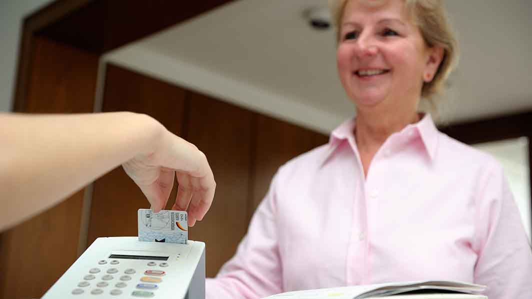 Patient steckt Versichertenkarte in ein ein Lesegerät. 